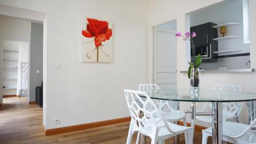 une salle à manger avec une table en verre et des chaises blanches dans l'établissement Rue Servandoni - Paris 6, à Paris
