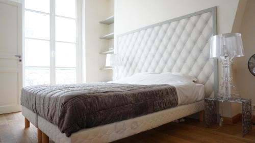 une chambre avec un grand lit blanc avec une grande tête de lit dans l'établissement Rue Servandoni - Paris 6, à Paris