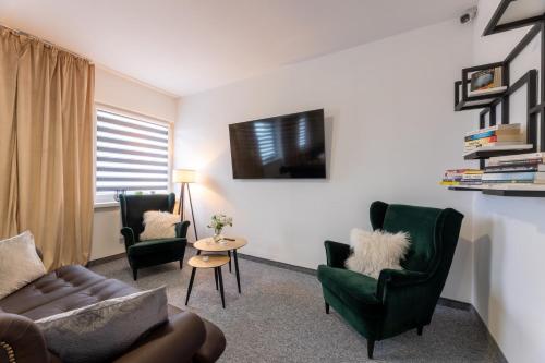 a living room with a couch and chairs and a tv at Awilla Ustka in Ustka