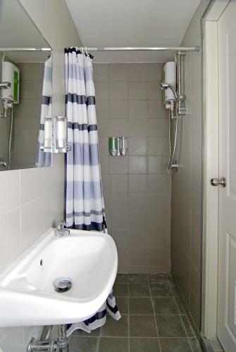 a bathroom with a white sink and a shower at Salika Hostel Patong Phuket in Patong Beach