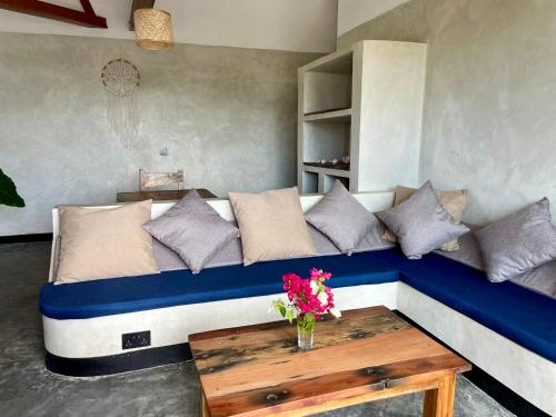 a couch with pillows and a table in a room at Baobab Bungalows in Jambiani