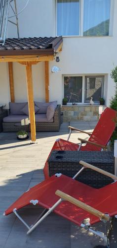 two red folding chairs sitting on a patio at Къща за гости Ози in Ovchartsi