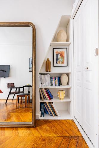 un miroir dans un couloir à côté d'une pièce avec des livres dans l'établissement Luminous Studio Oasis Steps from The Louvre, à Paris