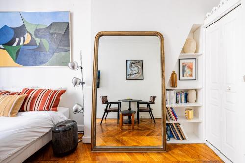 un miroir dans une chambre avec un lit et une table dans l'établissement Luminous Studio Oasis Steps from The Louvre, à Paris
