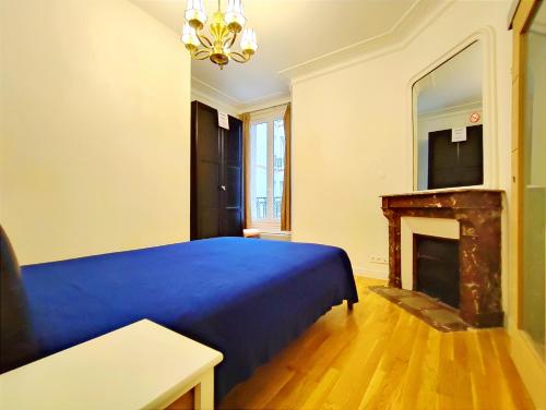 une chambre avec un lit bleu et une cheminée dans l'établissement Bd de Grenelle - Paris 15, à Paris