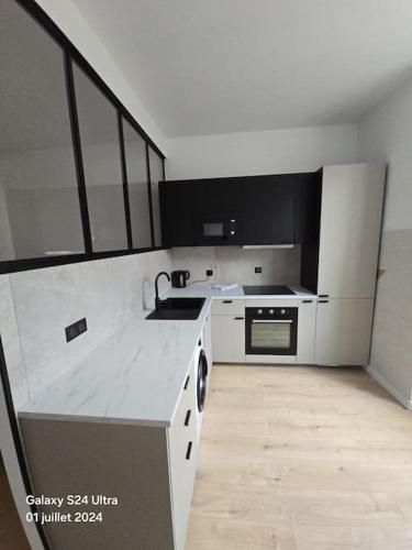 une cuisine blanche avec un évier et une cuisinière dans l'établissement Joli studio en centre-ville, à Corte