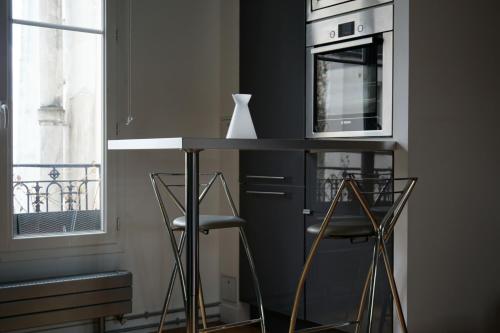 une cuisine avec un comptoir, un four micro-ondes et des tabourets dans l'établissement Avenue de la Grande Armee - Paris 17, à Paris