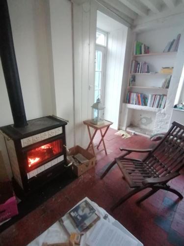 a living room with a fireplace and a chair at Natur und Sterne in Arleuf