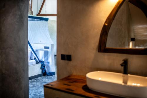 a bathroom with a sink and a mirror at Baobab Bungalows in Jambiani