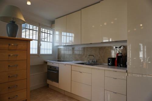 une cuisine avec des armoires blanches et un évier dans l'établissement Rue de la Chaussée d'Antin - Paris 9, à Paris