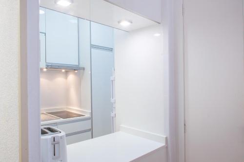 a kitchen with white cabinets and a refrigerator at Serisol Holidays in Benidorm