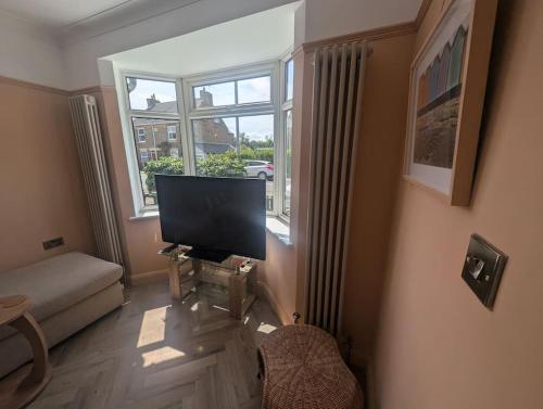 a living room with a flat screen tv and a window at Kemp's Kottage in Lowestoft