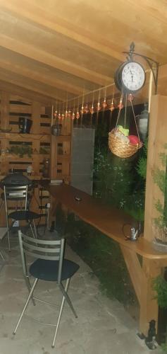 a room with a table and a clock and chairs at Къща за гости Ози in Ovchartsi