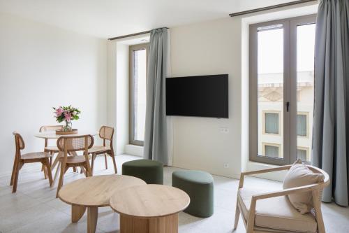 a living room with a table and a tv at Hôtel La Suite in Biarritz