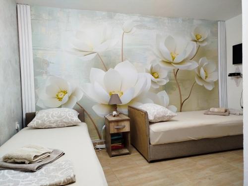 two beds in a room with white flowers on the wall at Vicky Apartments in Kotor