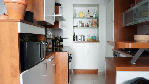 une cuisine avec des armoires blanches et un micro-ondes dans l'établissement Rue du Faubourg Saint Honore - Paris 8, à Paris