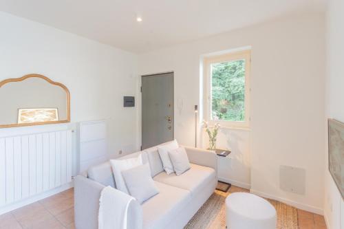 a white living room with a white couch and a window at Casa Vela by Rent All Como in Sala Comacina