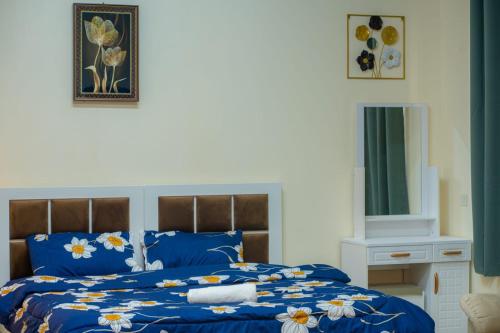 a blue bed with a blue comforter with flowers on it at BAITH AL JANNAH Luxury Family Room in Abu Dhabi