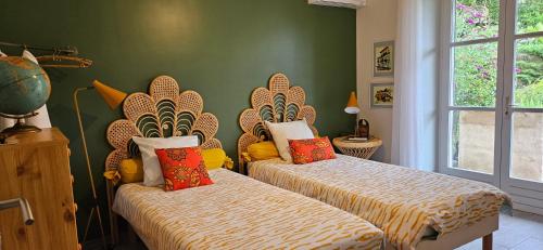 deux lits dans une chambre aux murs verts dans l'établissement Le Cottage des Mésanges, à Villefranche-de-Rouergue