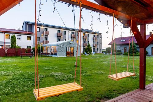three swings in a yard with a building at Awilla Ustka in Ustka