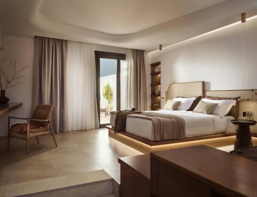 a bedroom with a bed and a desk and a chair at Anemelia Hotel Mykonos in Elia Beach