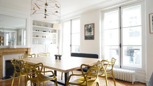une salle à manger avec une table en bois et des chaises jaunes dans l'établissement Rue de Penthièvre - Paris 8, à Paris