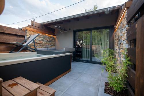 an outdoor patio with a stone wall and sliding glass doors at Sylvia Camping & Luxury Suites, Panel Hospitality Homes & Villas in Litochoro