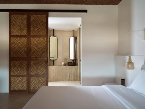 a bedroom with a white bed and a sliding door at Anemelia Hotel Mykonos in Elia Beach