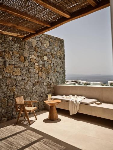 a room with a bed and a bench and a table at Anemelia Hotel Mykonos in Elia Beach