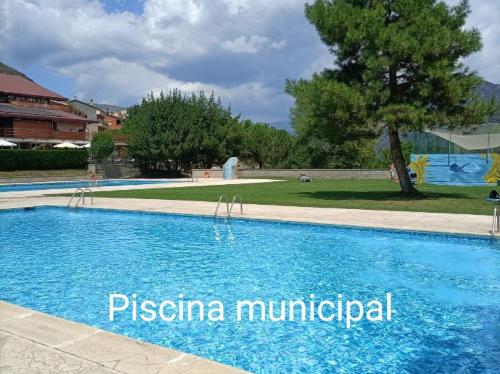 a large blue swimming pool with a tree in the background at Apartamento Can Jasana in Sant Jordi de Cercs