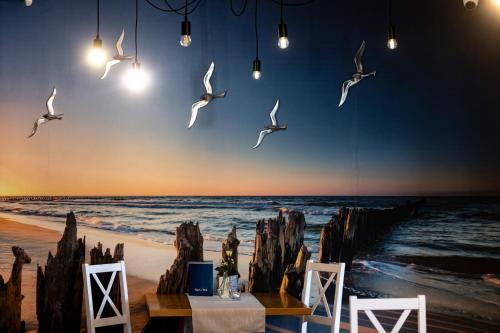 a painting of birds flying over a beach at Awilla Ustka in Ustka