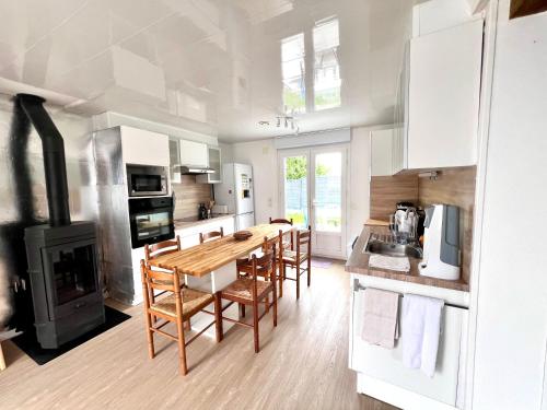 - une cuisine et une salle à manger avec une table et une cuisinière dans l'établissement Très belle Maison Familiale à 800m de la plage, à Loctudy