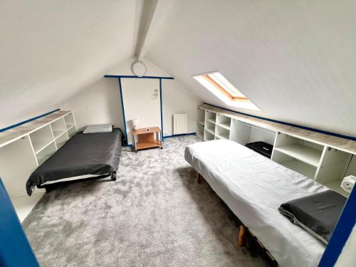 une chambre mansardée avec deux lits et une fenêtre dans l'établissement Très belle Maison Familiale à 800m de la plage, à Loctudy