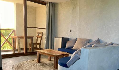 a living room with a blue couch and a table at Baobab Bungalows in Jambiani