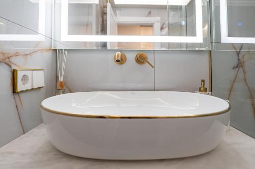 a white bath tub in a bathroom with a mirror at AMJ Royal Apartments - 120 - Royal Classic in Kaunas