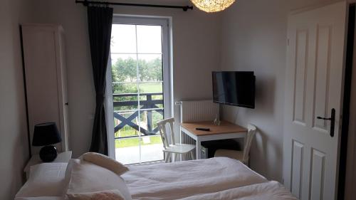 a bedroom with a bed and a desk and a window at Domek na Błotach in Karwieńskie Błoto Drugie