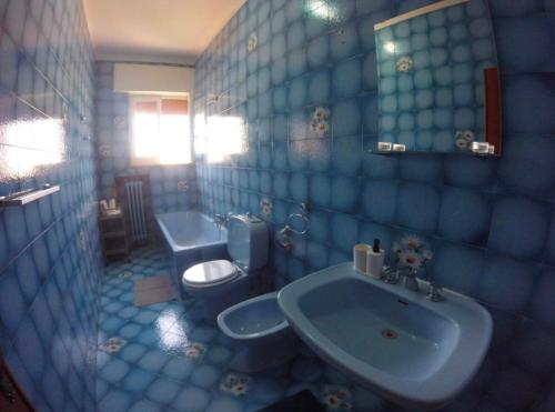 a blue tiled bathroom with a toilet and a sink at Stanza matrimoniale bagno privato in Mola di Bari