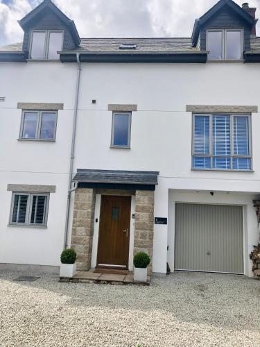 a white house with a brown door and garage at Guest Room with Parking Near St Ives & Penzance in Penzance