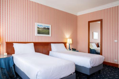 a hotel room with two beds and a mirror at Golf Hotel Cavaglià in Cavaglià