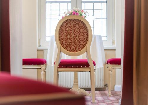 a chair with a red seat and a table with flowers at Aviano Boutique Hotel in Vienna