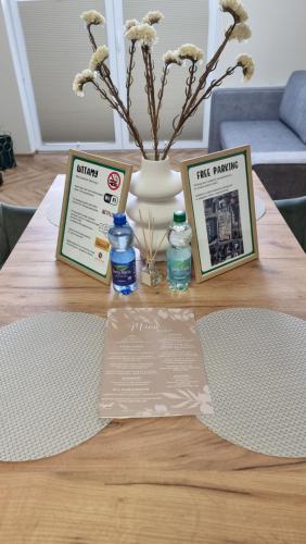 a table with two pamphlets and a vase with flowers at Apartament w Centrum Luksusowy, Klimatyzacja, Full Opcja, Zameldowanie 24h, Duży Parking, Balkon, PlayStation 5, Ekspres, Netflix, Winda, FV, Nowy Budynek in Starogard Gdański