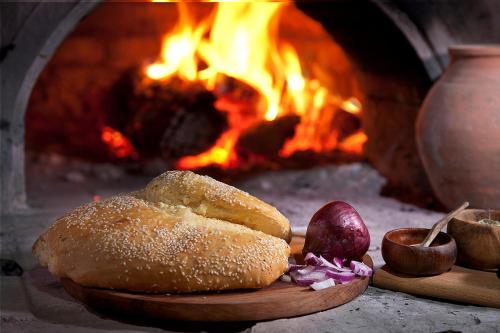 a loaf of bread on a cutting board next to a fireplace at Family Hotel Arkan Han in Trigrad