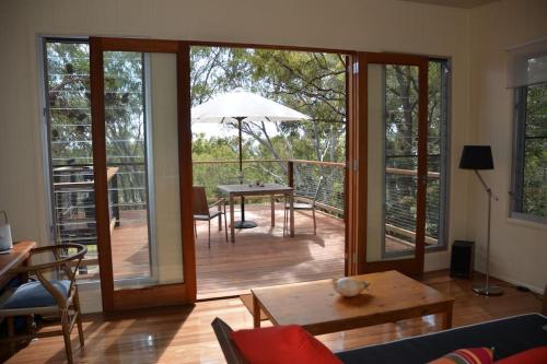 a living room with a patio with a table and umbrella at Mia Mia in K'gari Island (Fraser Island)