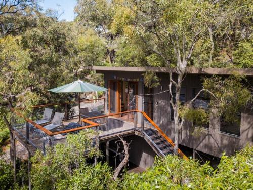 a house with a deck with an umbrella and a chair at Mia Mia in K'gari Island (Fraser Island)