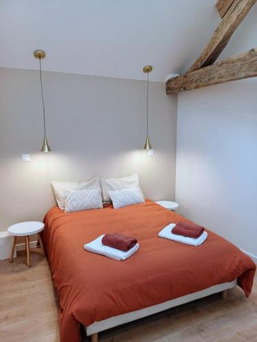 - une chambre avec un grand lit orange et 2 serviettes dans l'établissement L'orée du bois, à Colombiers