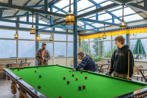 a group of people standing around a pool table at Zostel Kalpa in Kalpa
