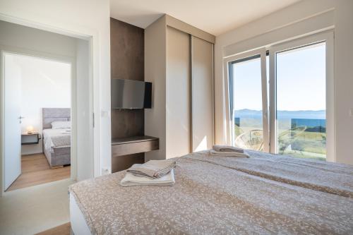 a bedroom with a large bed with a large window at Villa La Vista e Bella in Kožino