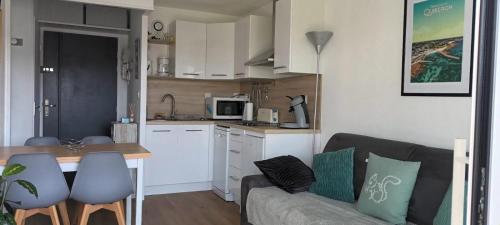 un salon avec un canapé et une cuisine dans l'établissement appartement cocon à Quiberon dans résidence calme, plages et centre ville à pied ou à vélo pour 2 à 4 personnes, à Quiberon
