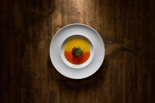 a bowl of soup on a wooden table at Hotel Des Alpes in La Villa