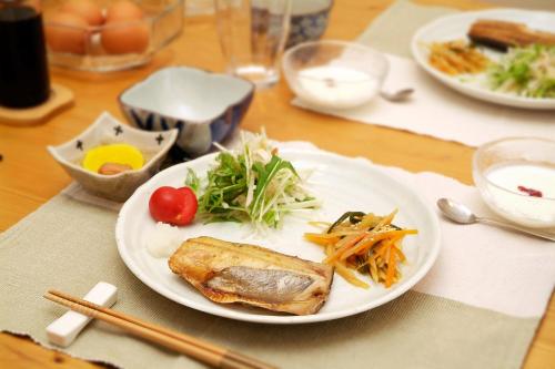 a white plate with food on a wooden table at Akane-yado in Nakafurano
